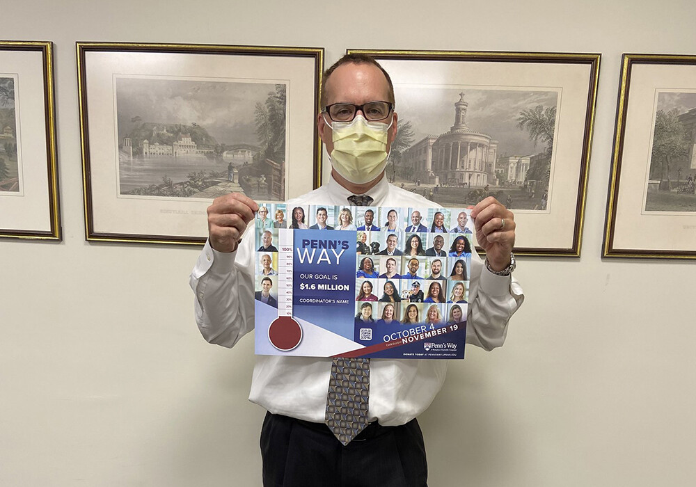 Penn's Way Campaign 2021 volunteer wearing a mask holding a poster