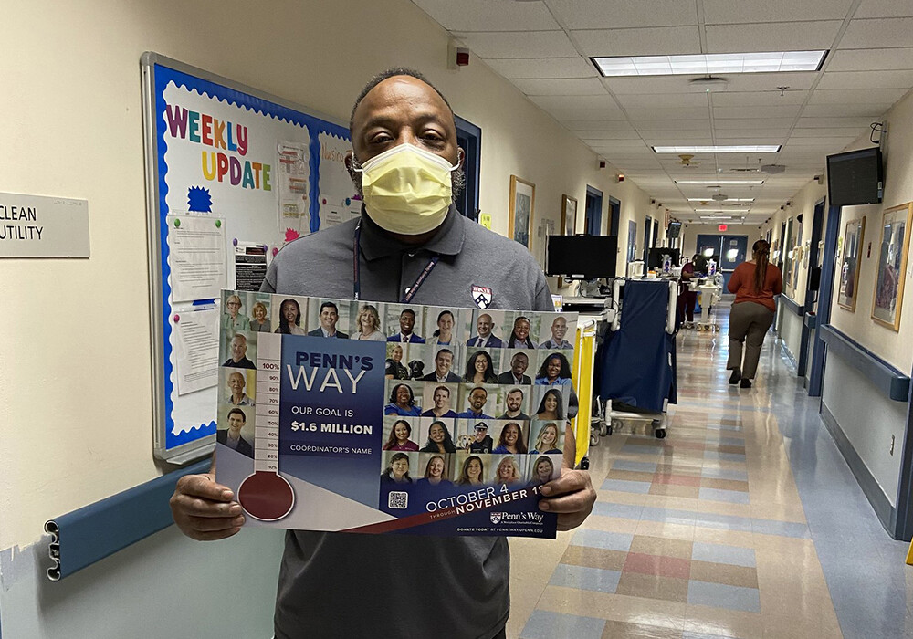 Penn's Way Campaign 2021 volunteer wearing a mask in a hallway holding a poster