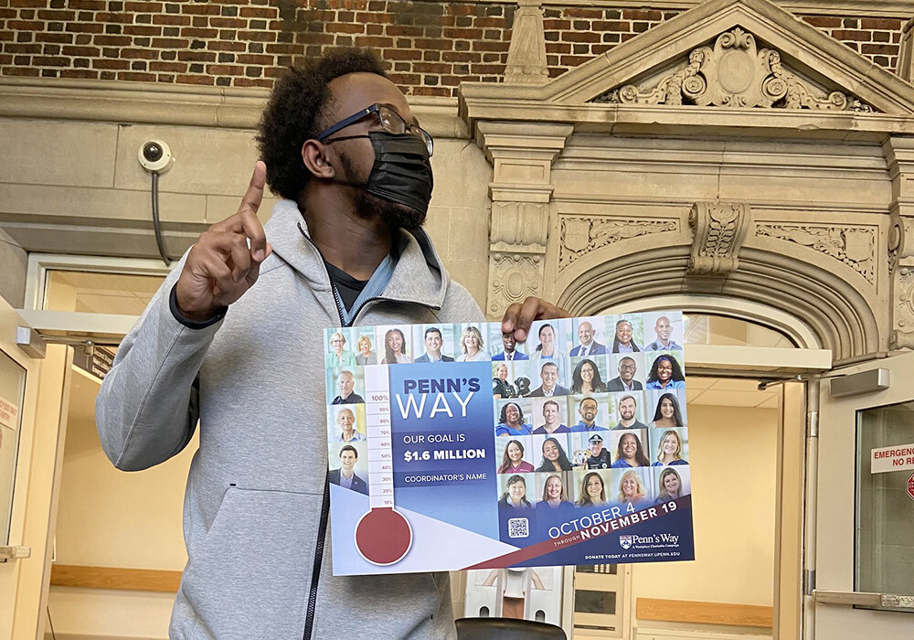 Penn's Way Campaign 2021 outside volunteer in a mask pointing up and holding poster