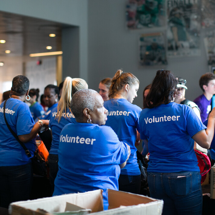 back view of people wearing t-shirts printed with volunteer 