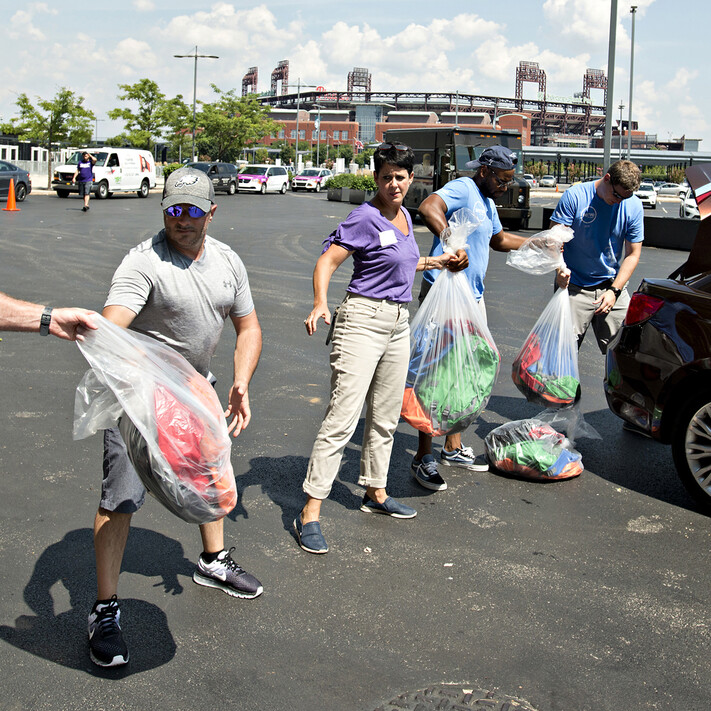 volunteers passing bags of donations into a car